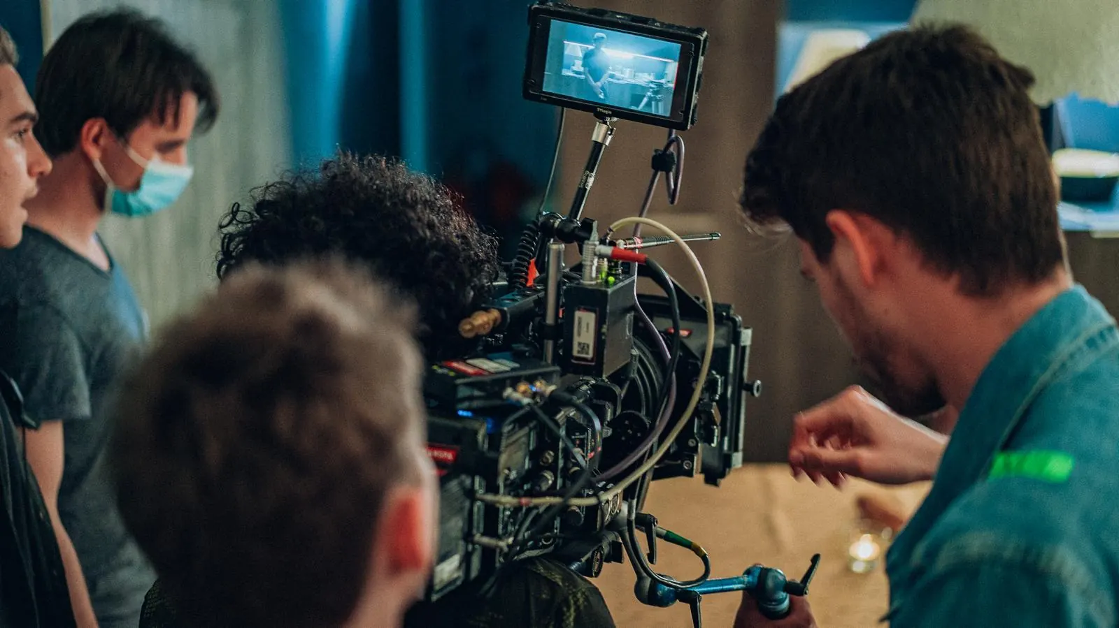 Sur un tournage, l’équipe technique se penche sur une caméra de cinéma et son moniteur de retour